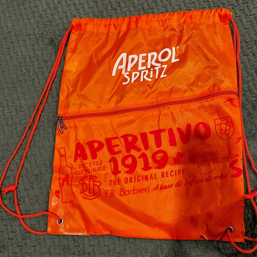 Aperol Spritz drawstring bag with front zipper pocket.